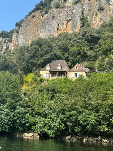 a house on the side of a hill next to the water at La Terrasse sur La Roque-Gageac in Vézac