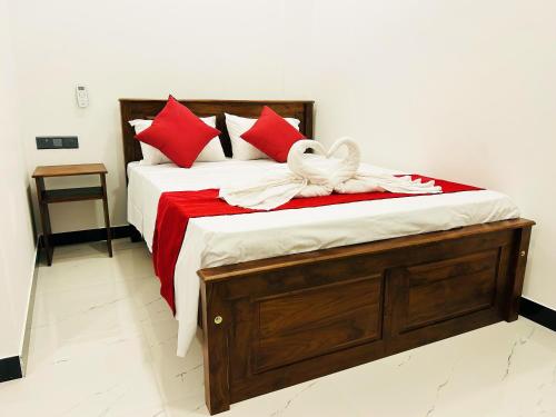 a bed with red pillows and a white bow on it at Nushi Inn in Katunayaka