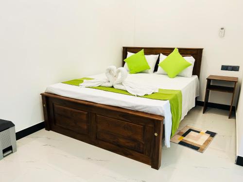 a bedroom with a large bed with green pillows at Nushi Inn in Katunayaka