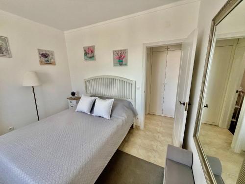 a bedroom with a bed with white sheets and a mirror at Paradise in Costa da Caparica