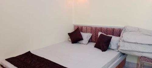 a small bed with three pillows on it at Mukherjee Lodge in Rāmpur Hāt