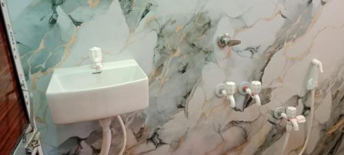 a bathroom with a white urinal on a marble wall at Mukherjee Lodge in Rāmpur Hāt