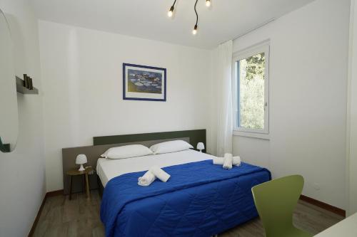a bedroom with a bed with blue sheets and a window at Appartamenti Pratone in Garda