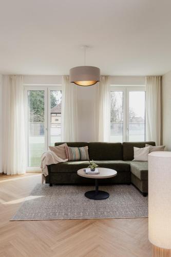 a living room with a green couch and a table at LÆKE Apartments - Lindau am Bodensee in Lindau