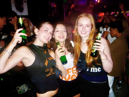 three girls holding beer bottles in a club at Zostel Phuket, Patong Beach Hostel in Patong Beach