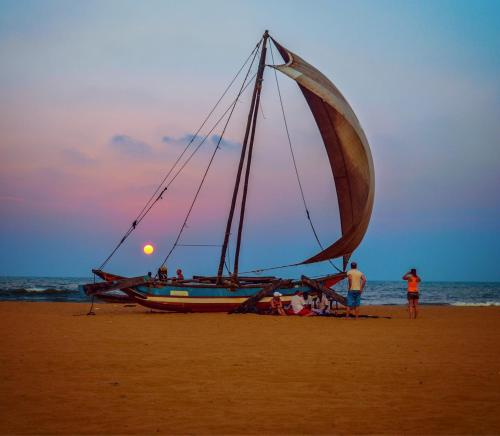 a boat on the beach with people on the beach at Breezy Villa in Negombo