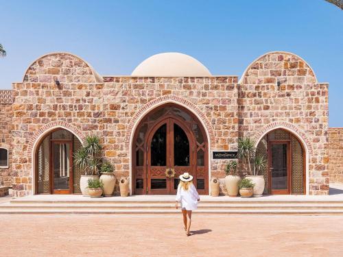 a woman walking in front of a brick building at Movenpick Resort El Quseir in Quseir