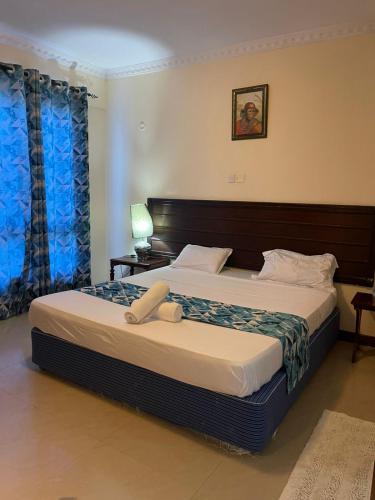 a bedroom with a large bed with a wooden headboard at Topaz Apartments Shanzu in Mombasa