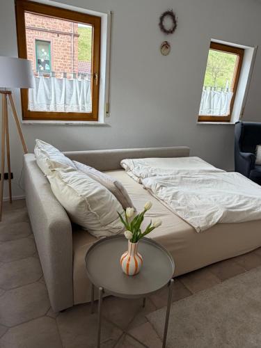 a bedroom with a couch and a table with a vase on it at Ferienwohnung Sensbachtal in Untersensbach