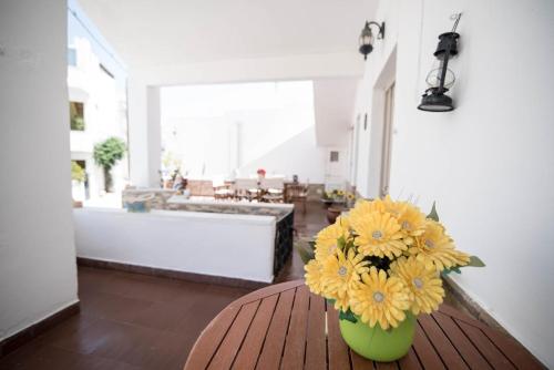 a green vase with yellow flowers sitting on a table at Naxian Harmony 300m from the beach in Naxos Chora