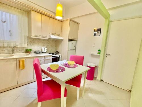 a kitchen with a white table and pink chairs at ZEN, Oneiropagida, Aegina in Vathí