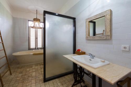 a bathroom with a sink and a tub and a mirror at Abipraya Ubud in Ubud