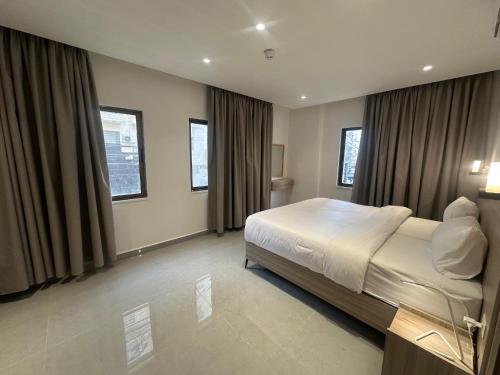 a bedroom with a large bed and some windows at Masaken Hotel Apartment in Amman