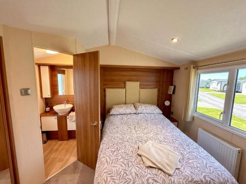 a small bedroom with a bed and a sink at Bluebird Skies - A cosy getaway in Great Yarmouth