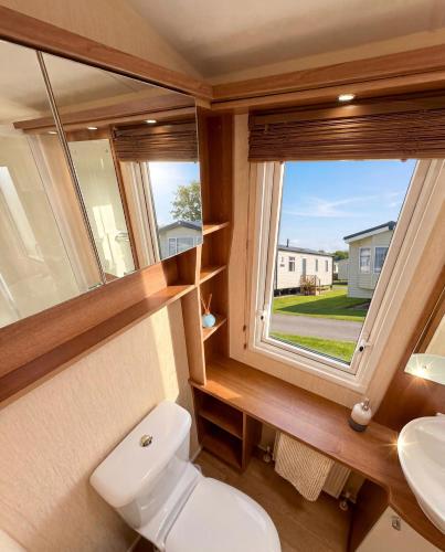 a small bathroom with a toilet and a window at Bluebird Skies - A cosy getaway in Great Yarmouth
