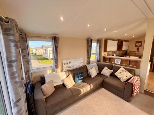 a living room with a brown couch and a kitchen at Bluebird Skies - A cosy getaway in Great Yarmouth
