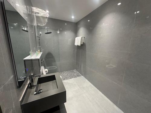 a bathroom with a sink and a shower with a mirror at Masaken Hotel Apartment in Amman