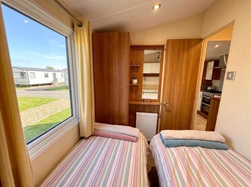 two beds in a small room with a window at Bluebird Skies - A cosy getaway in Great Yarmouth