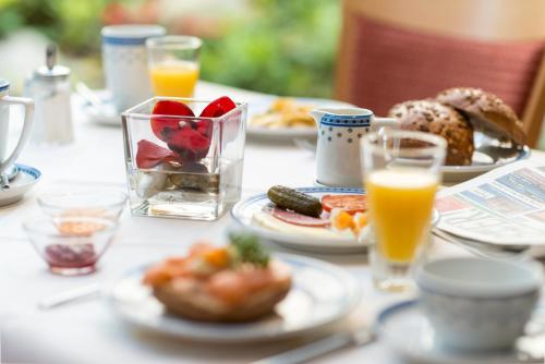 une table avec des assiettes de nourriture et des verres de jus d'orange dans l'établissement Ambient Hotel Zum Schwan, à Gelsenkirchen