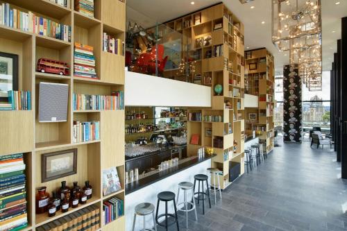 a bookstore with shelves of books and stools at citizenM Tower of London in London