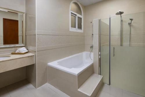 a bathroom with a shower and a sink and a tub at The Villa Jumeirah in Dubai