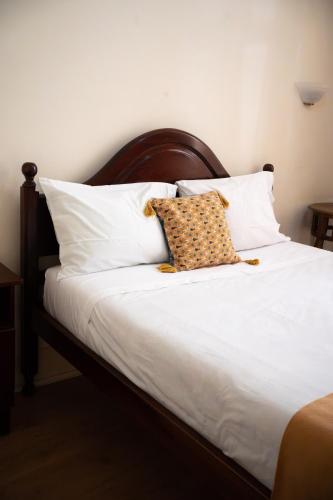 a bed with white pillows and a brown and white pillow at Corações Unidos "A Pensão" in Alcobaça