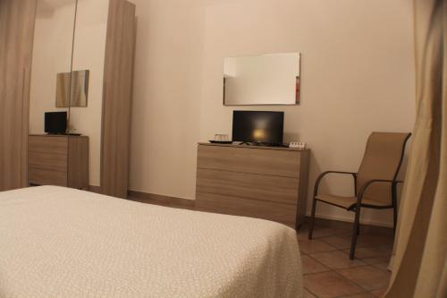 a bedroom with a bed and a tv and a chair at Camera confortevole tra Roma e Ostia in Acilia