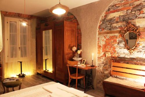 ein Schlafzimmer mit einer Ziegelwand, einem Bett und einem Tisch in der Unterkunft Le Dame Della Cortesella B&B in Como