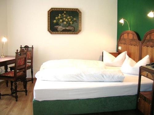 a bedroom with a bed with a desk and a painting on the wall at Historisches Genusshotel Löwen in Schopfheim