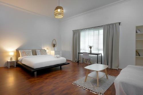 a white bedroom with a bed and a desk at The Villa Jumeirah in Dubai