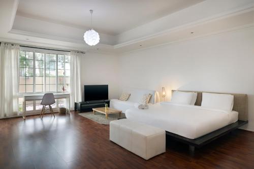 a white bedroom with a large white bed and a couch at The Villa Jumeirah in Dubai