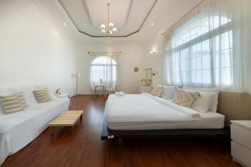 a white bedroom with a large bed and a couch at The Villa Jumeirah in Dubai
