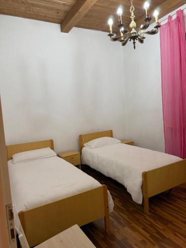 zwei Betten in einem Zimmer mit Kronleuchter in der Unterkunft Aurea in Castrocaro Terme