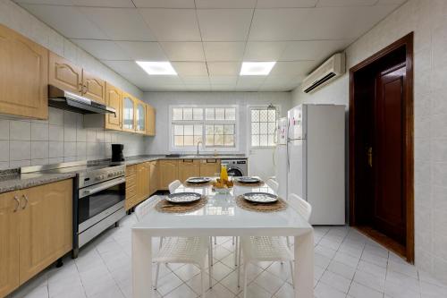 a kitchen with a white table and a white refrigerator at The Villa Jumeirah in Dubai
