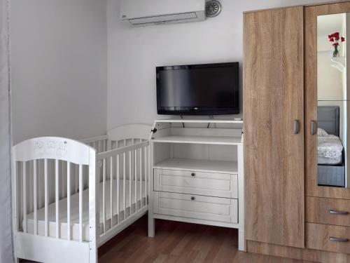 a baby room with a crib and a tv at Apartment Orange Blossom First Line & Pool 2 in Bijela
