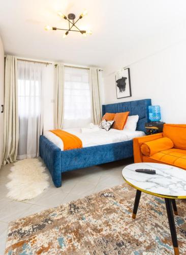 a bedroom with a blue bed and an orange couch at Cynergy Home in Nairobi