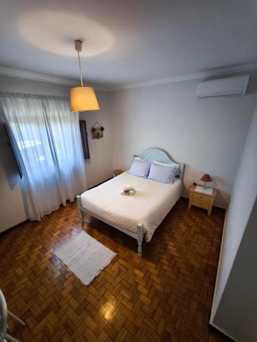 a bedroom with a white bed and a window at Casa das Flores in Santo Tirso