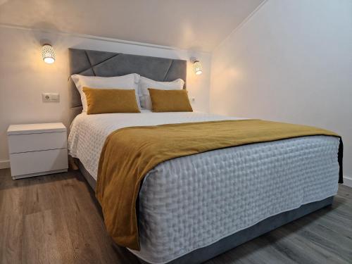 a bedroom with a large bed with yellow pillows at Stay Lombinho in Porto da Cruz
