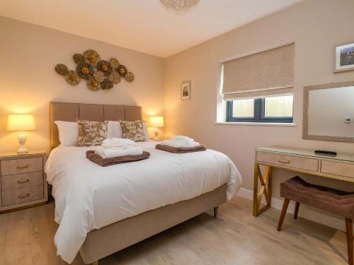 a bedroom with a bed and a desk and a mirror at Swing Bridge Cottage in Brandesburton