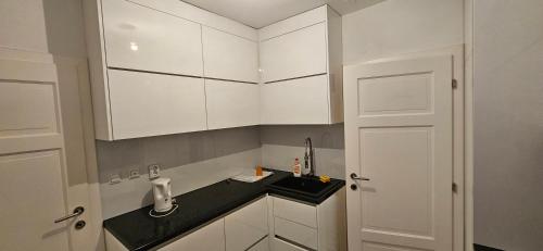 a white kitchen with a sink and white cabinets at Apartman Novak Prijedor in Prijedor