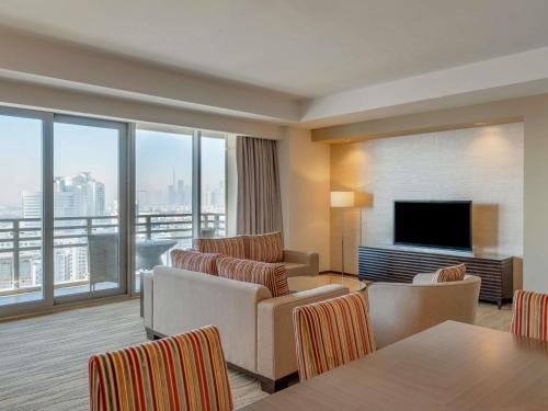 a hotel room with chairs and a flat screen tv at Swissôtel Living Al Ghurair Centre Dubai in Dubai