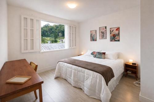 a white bedroom with a bed and a window at Casa Aconchegante com Vista pertinho do Centro Histórico in Petrópolis