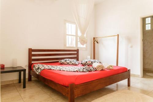 a bedroom with a wooden bed with red sheets at Vila Marilyn in São Tomé