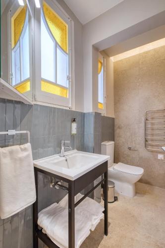 a bathroom with a sink and a toilet and windows at NORFOLK Suites in Sliema