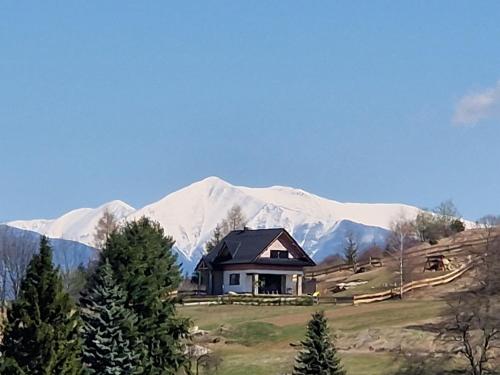 a house in front of a snow covered mountain at Chata Elegant in Bešeňová
