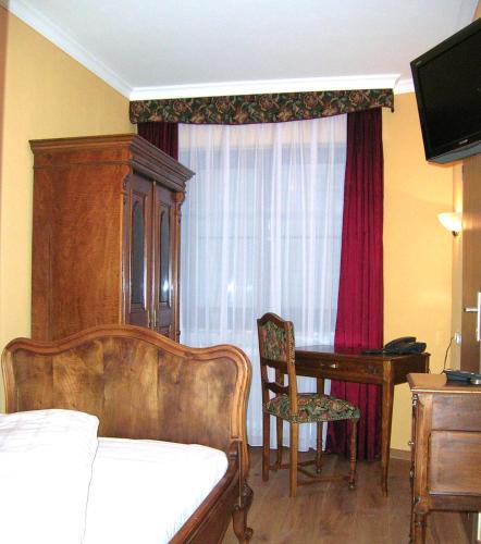 a bedroom with a bed and a table and a desk at Historisches Genusshotel Löwen in Schopfheim