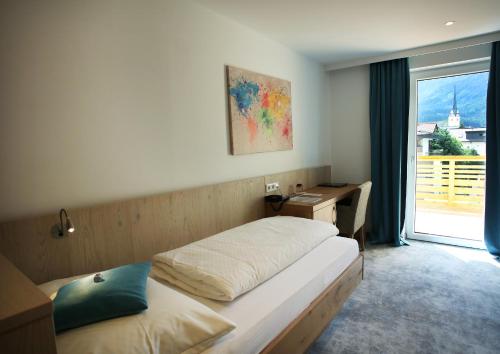 a bedroom with a bed and a desk and a window at Aktiv- und Wellnesshotel Gutjahr in Abtenau