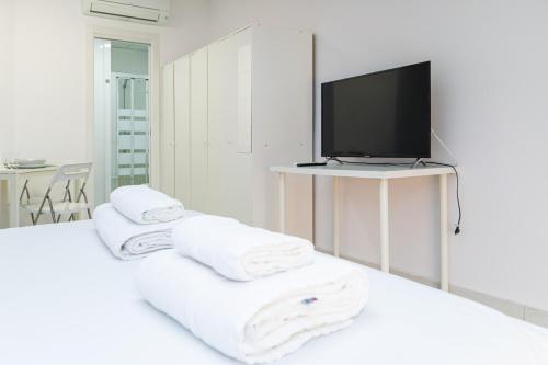 Ein weißes Zimmer mit Handtüchern auf einem Bett und einem Fernseher in der Unterkunft Still Loft in Coslada