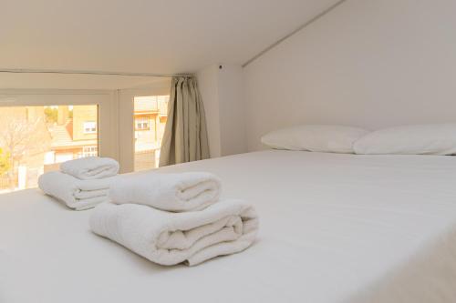 ein weißes Bett mit Handtüchern darauf in der Unterkunft Still Loft in Coslada