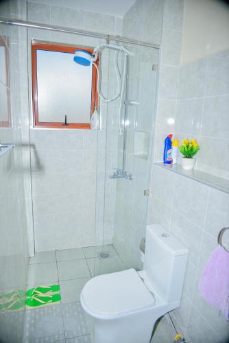 a white bathroom with a shower and a toilet at Savana Abode-Nakuru CBD in Nakuru